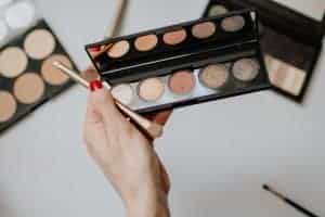 Woman holding a makeup palette and brush