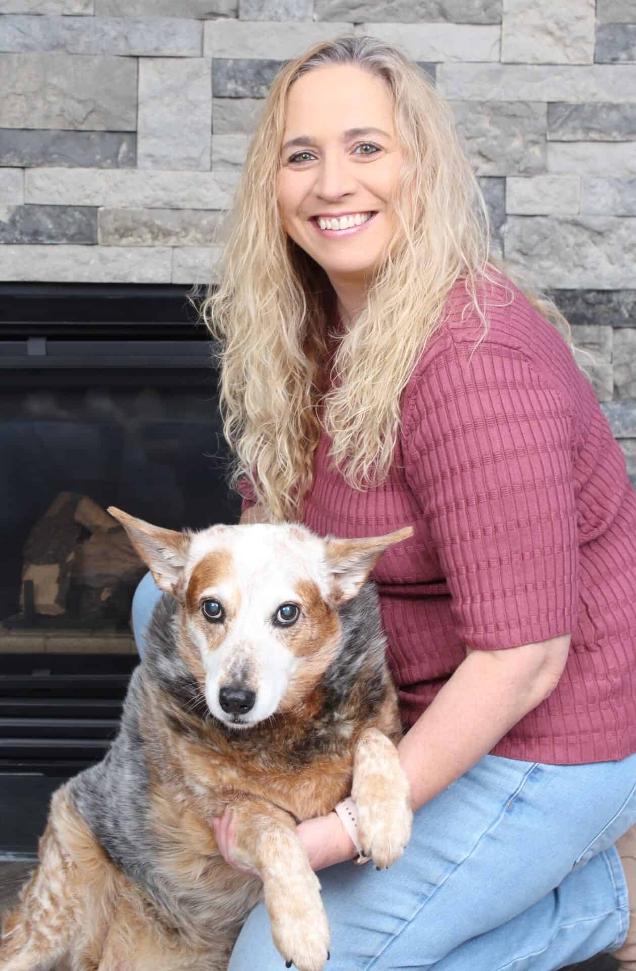 Woman smiling with dog in front of fireplace