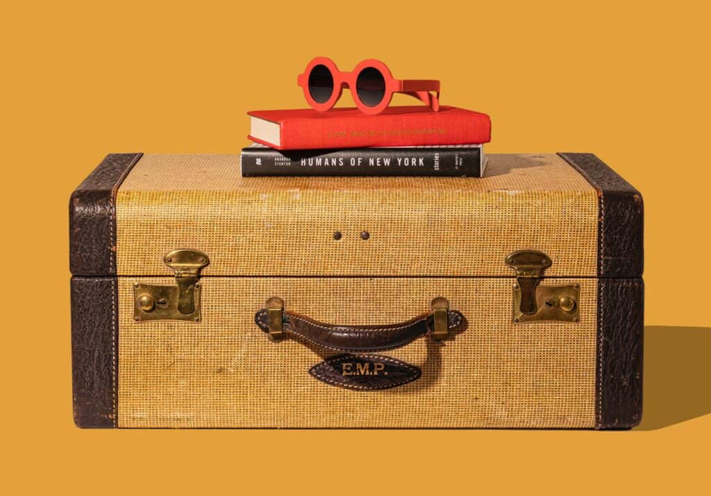 Tan suitcase with red sunglasses on top