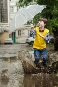 Kid holding an umbrella in a muddy puddle