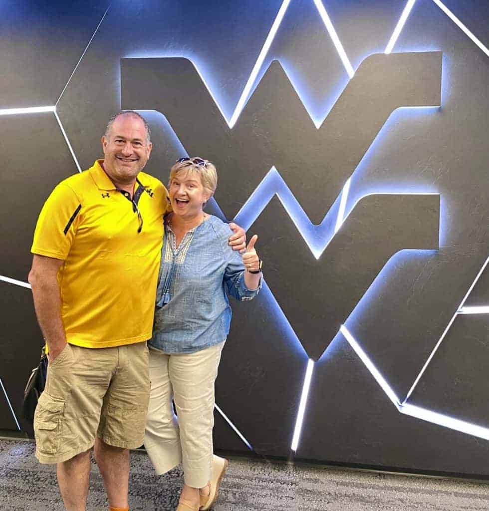 Man and woman standing in front of blue WV sign