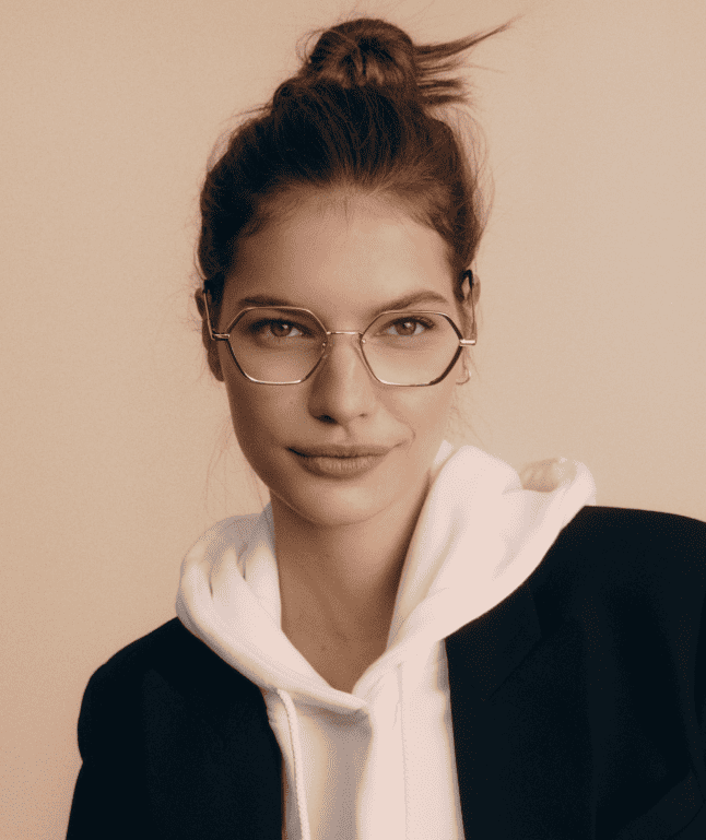 Woman wearing metal glasses and a white hooded sweatshirt