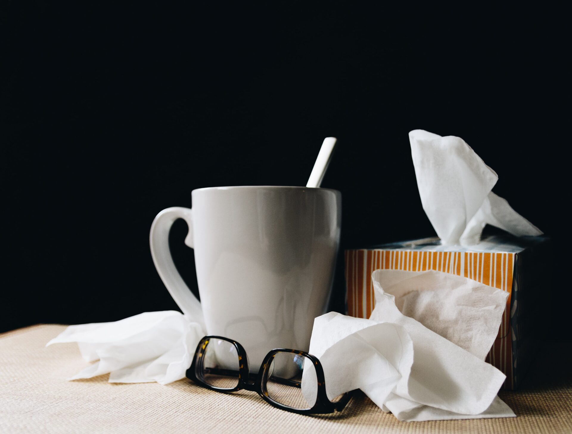 White mug with box of tissues and a pair of glasses