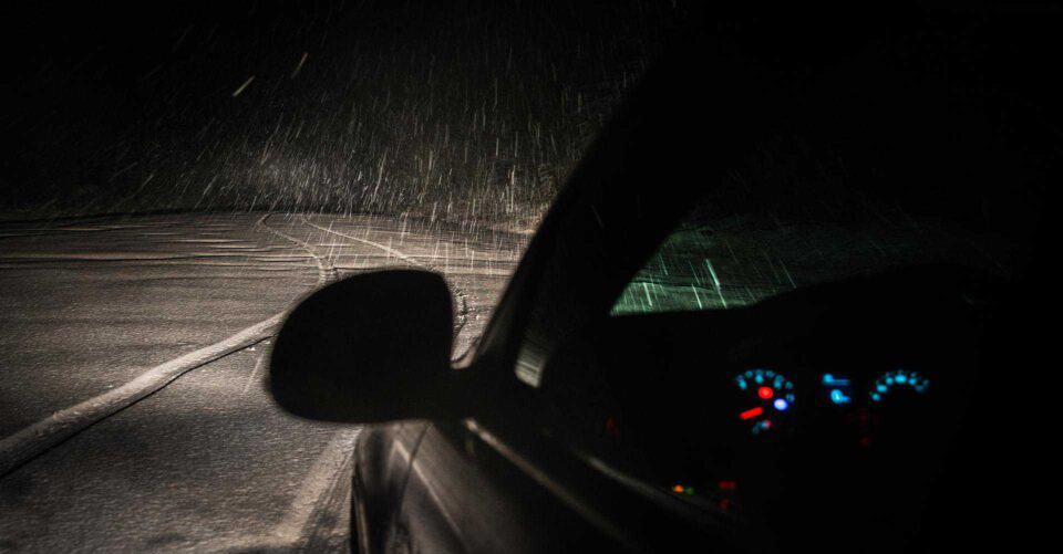 Car driving in the dark with snow on the road