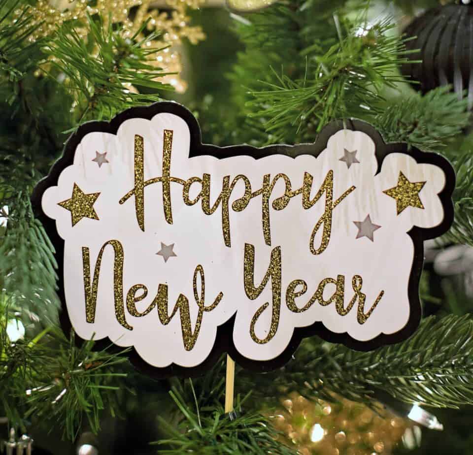 Happy New Year in gold font in green pine tree